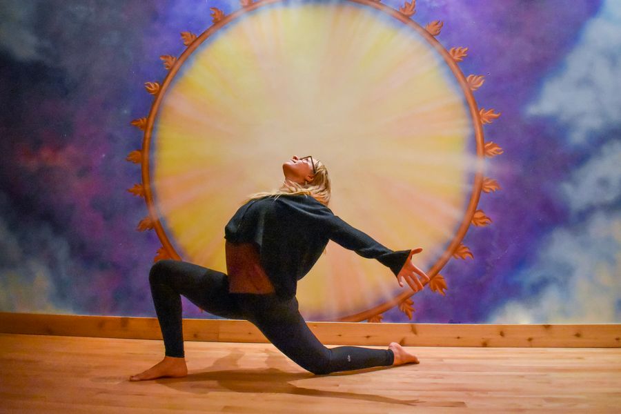 A low lunge with the chest lifted and the arms swept back, at the sun mural