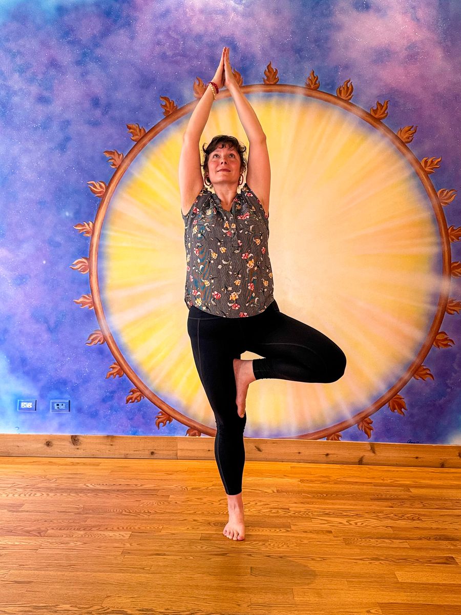 Tree pose with the hands together overhead, framed by the painted sun