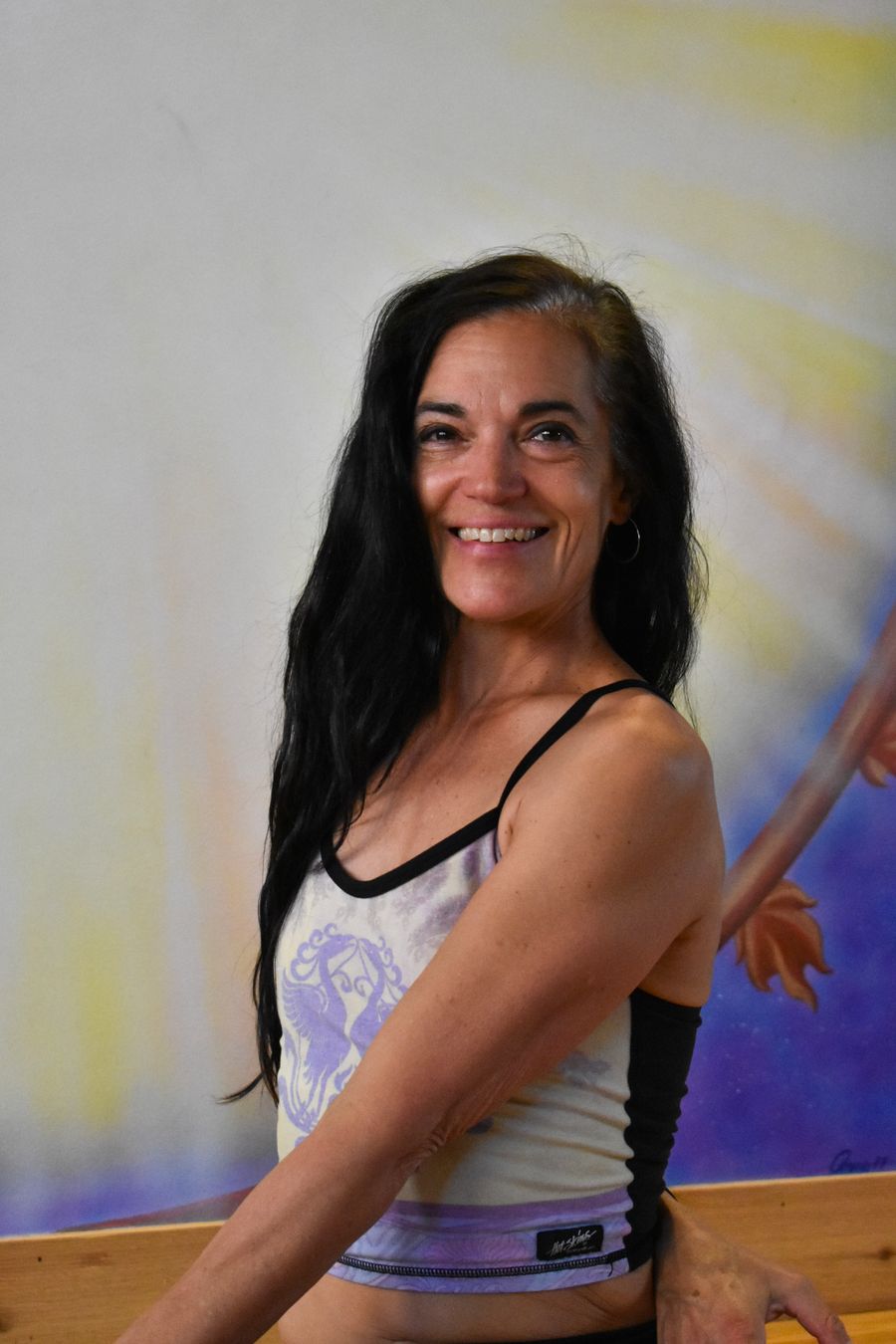 A smiling portrait in front of the sun mural