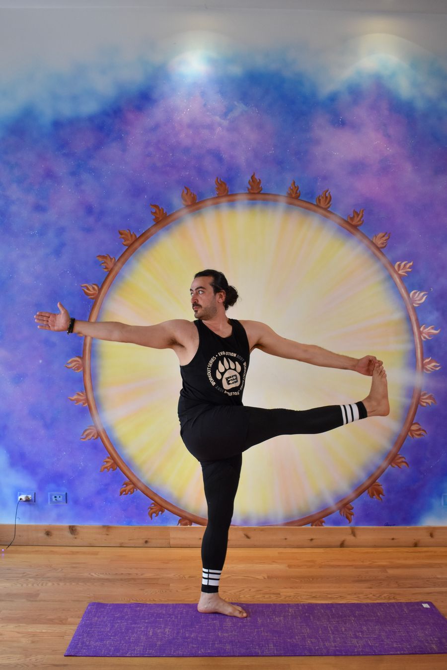 A standing balance holding one foot out to the side, at the sun mural