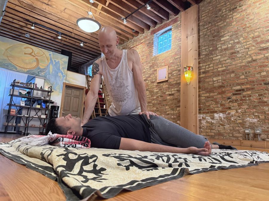 Rich working on a client who lies on a floor mat in the studio