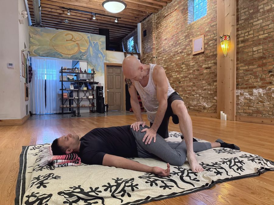 Rich pressing along a client's hip and thigh on the floor mat