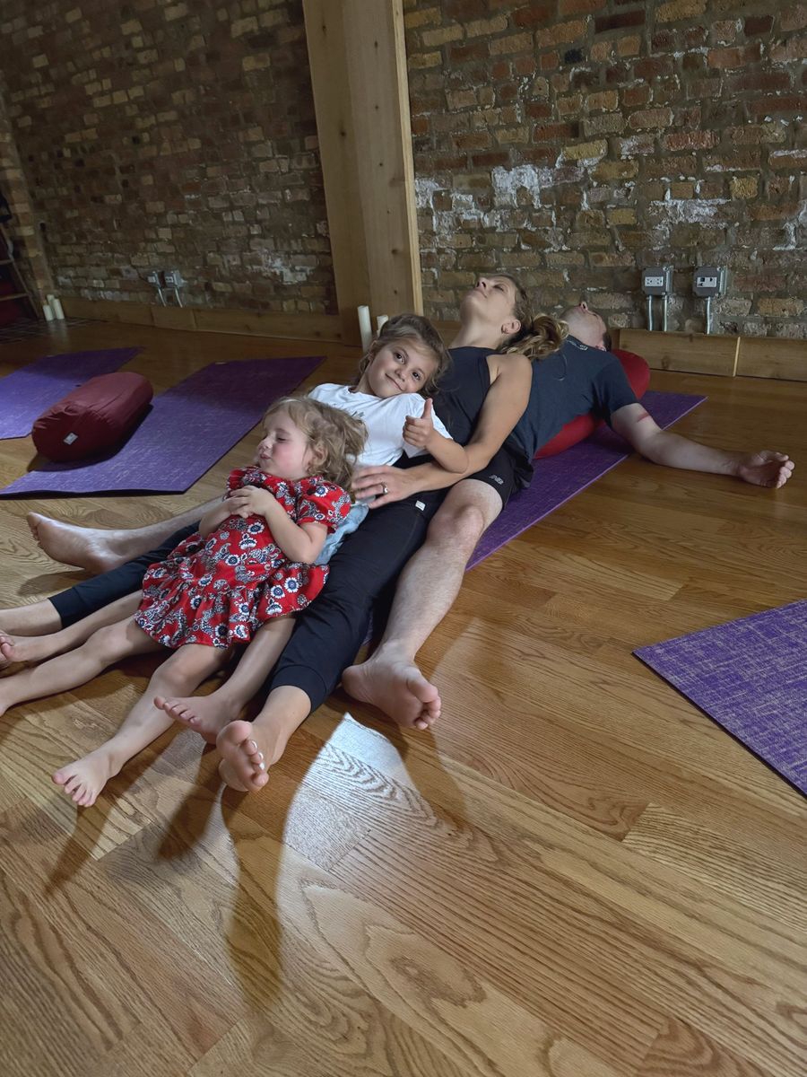 Two little girls resting on their parents at the end of Family Yoga