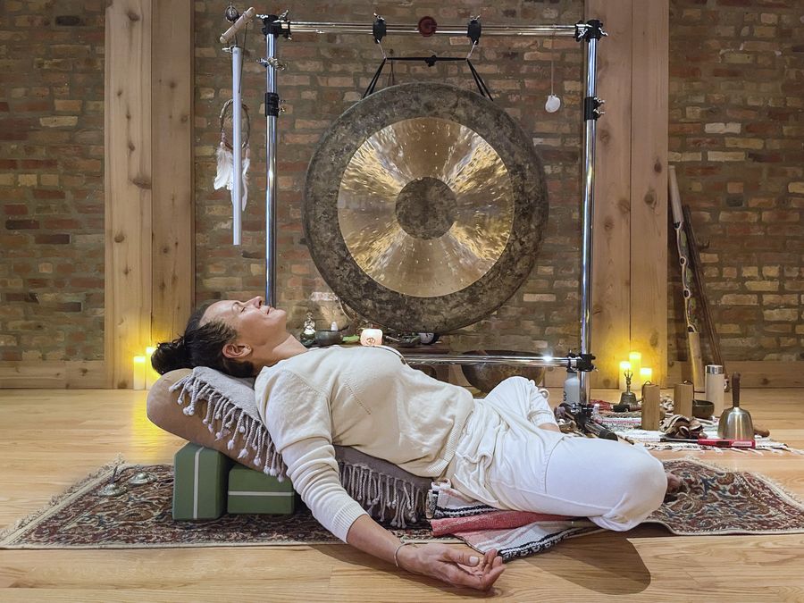 A student resting on a bolster and blocks in front of the gong