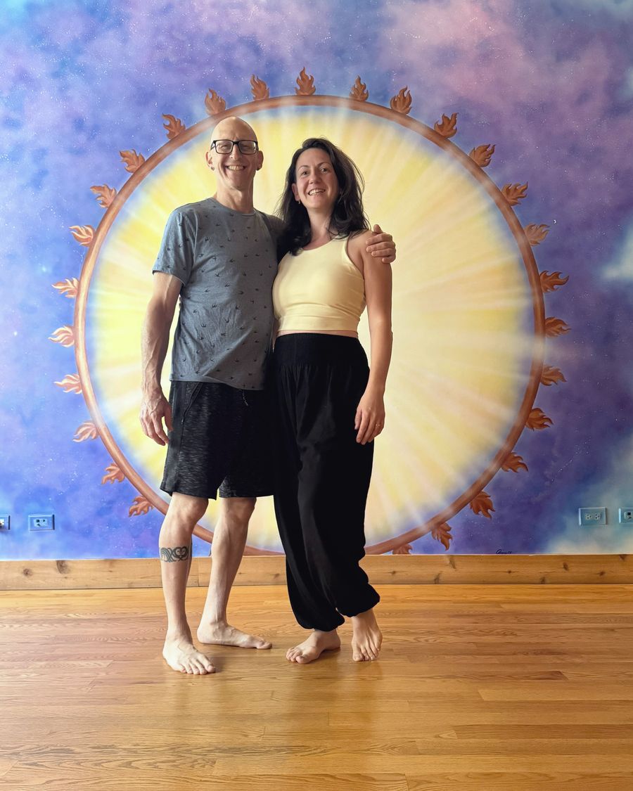 Rich and Nora smiling together in front of the painted sun mural