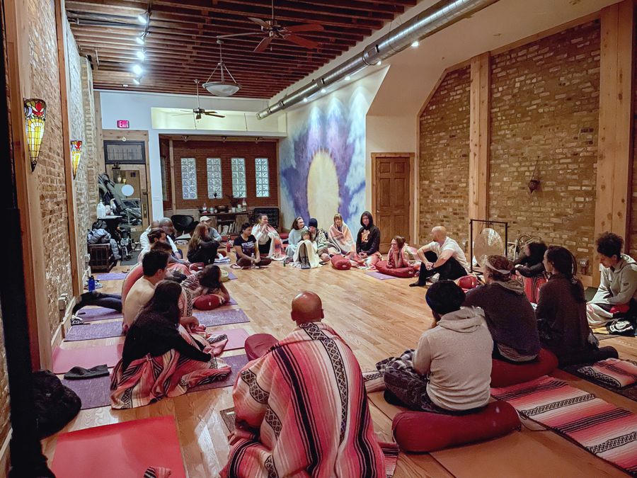 A group sitting in a circle on cushions in the studio