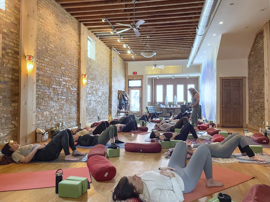 A full class resting on mats in the long brick-walled studio