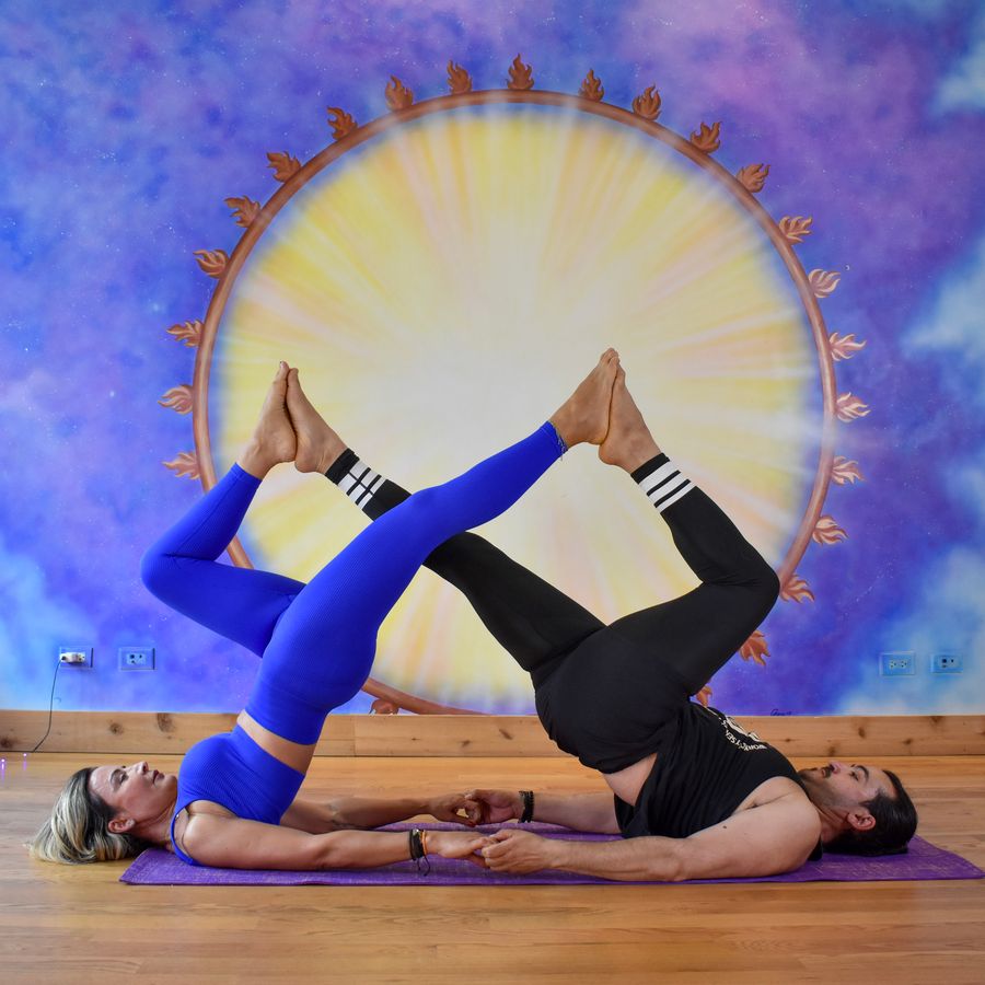 Two people lying head to head with their legs lifted and crossed, at the sun mural