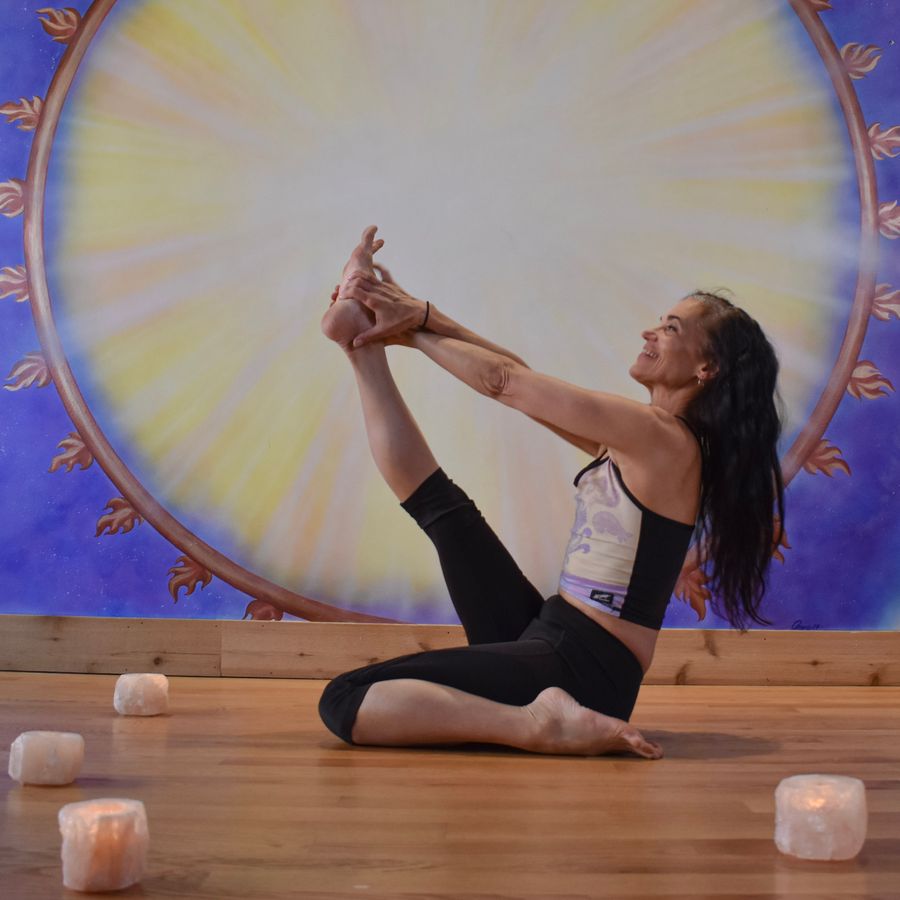 A seated balance holding one foot up high, in front of the sun mural