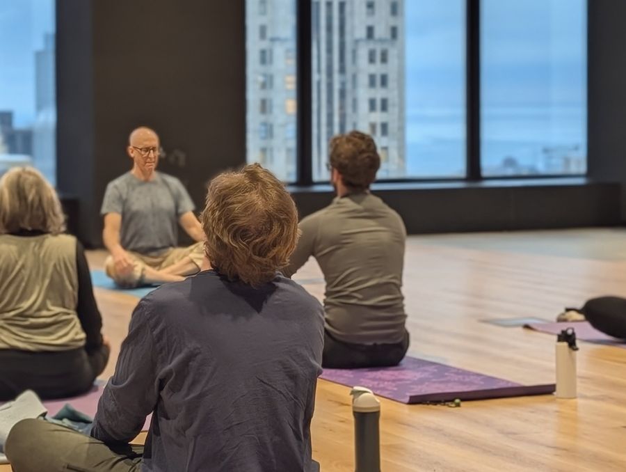 Rich leading a team yoga class in a downtown Chicago office, the skyline behind him